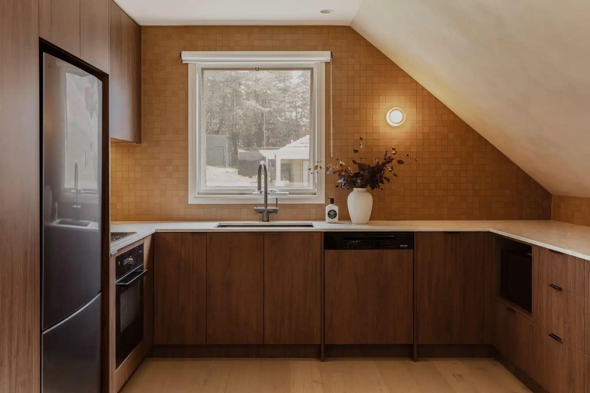 Modern kitchen with wood cabinets, tiled backsplash, and a window above the sink