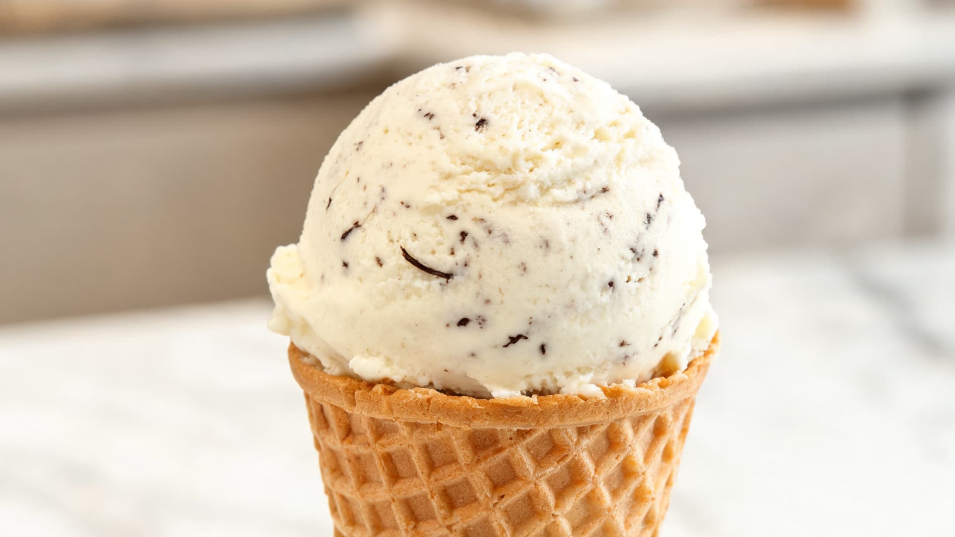 vanilla gelato scoop in cone cup smooth creamy texture with vanilla specks soft natural light dessert shop