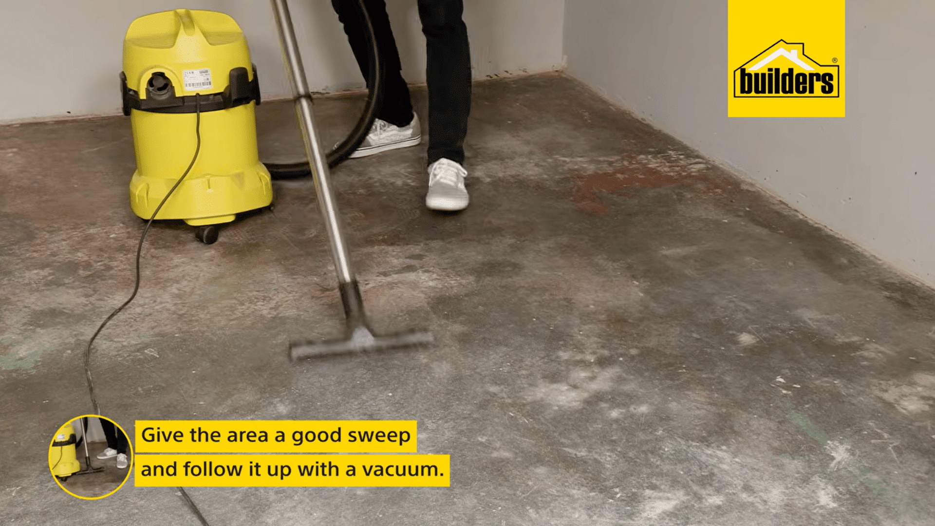 a person vacuums dust from a scraped concrete floor after sweeping to prepare the surface before applying fresh floor paint