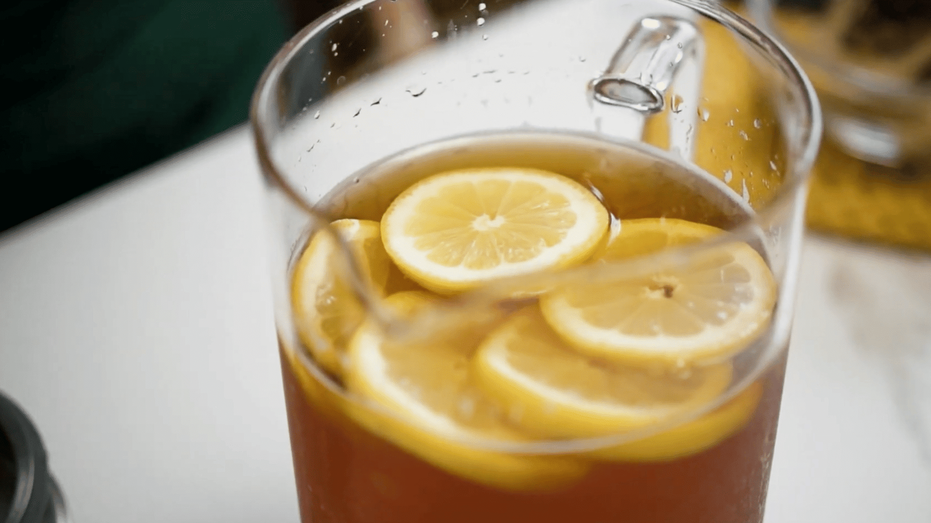 Glass pitcher of homemade iced tea topped with fresh lemon slices and ready to serve.
