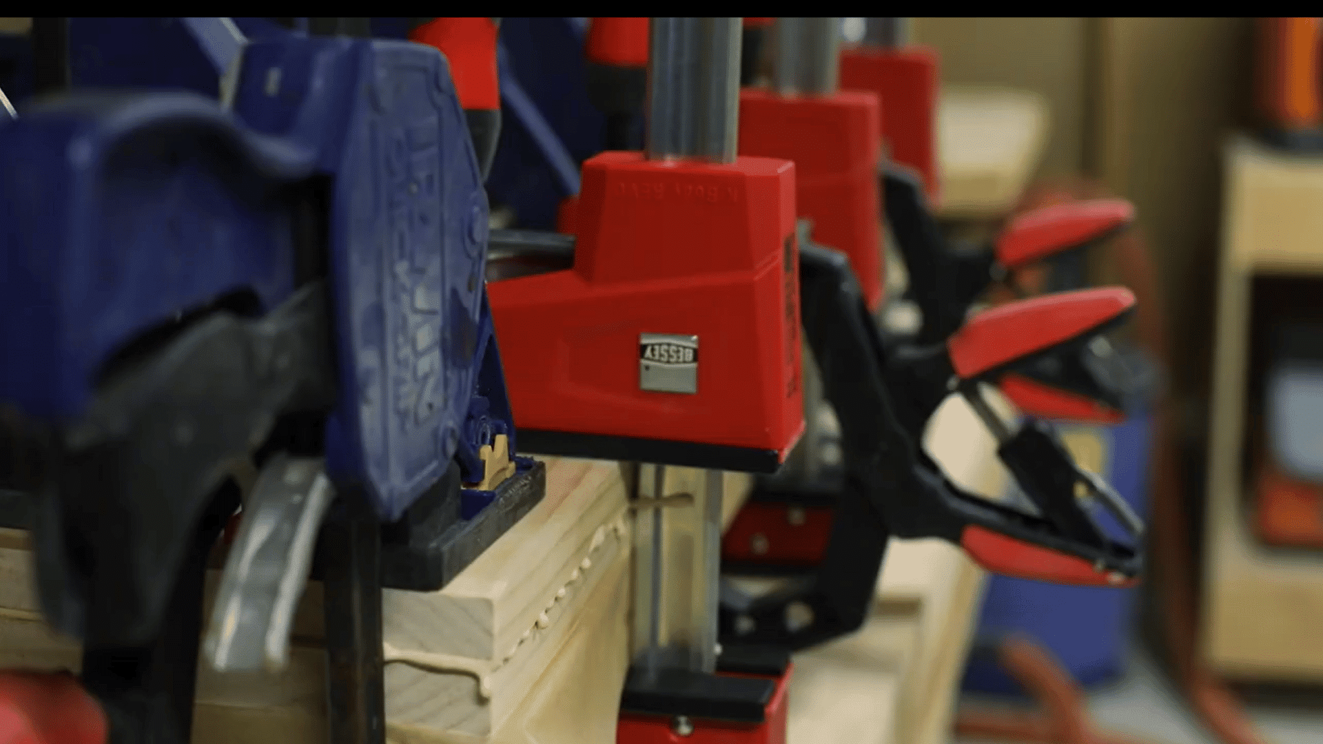 pine boards secured tightly with several clamps while the wood glue sets during shelf lamination