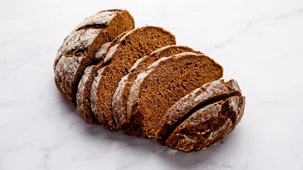 sliced rye bread loaf showing dense texture and wholesome grain appearance on a wooden surface with rustic presentation