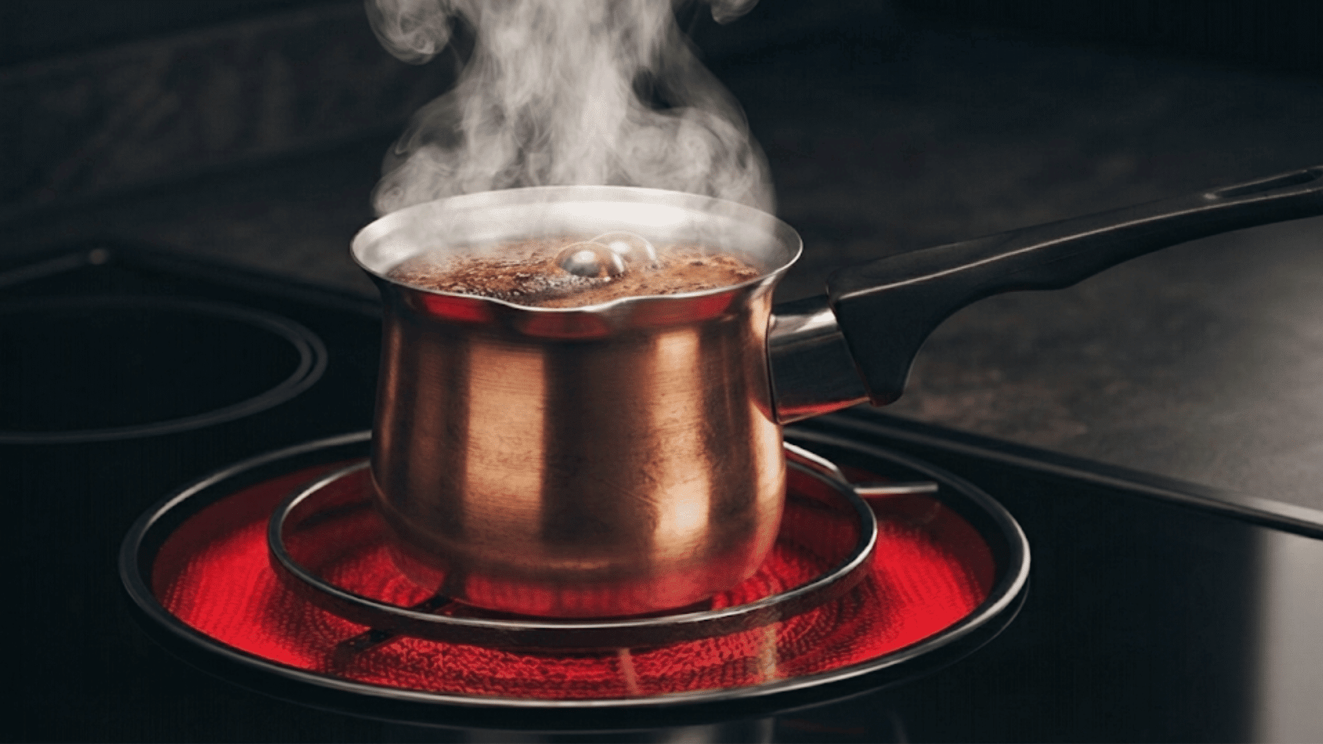 steaming pot of coffee boiling on an electric stove with bubbles rising from the surface and steam filling the air