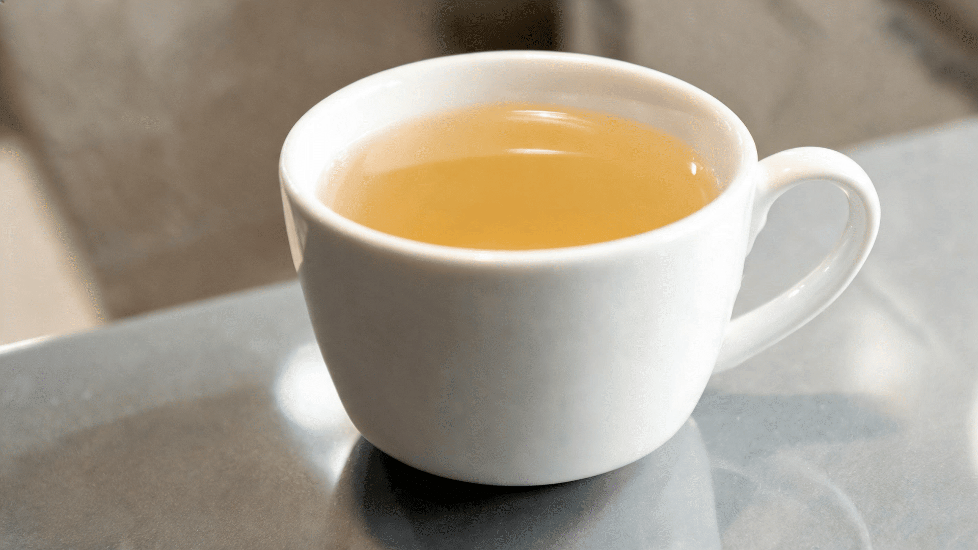 Warm herbal tea in a white cup representing a soothing drink for digestion and heartburn-friendly wellness.
