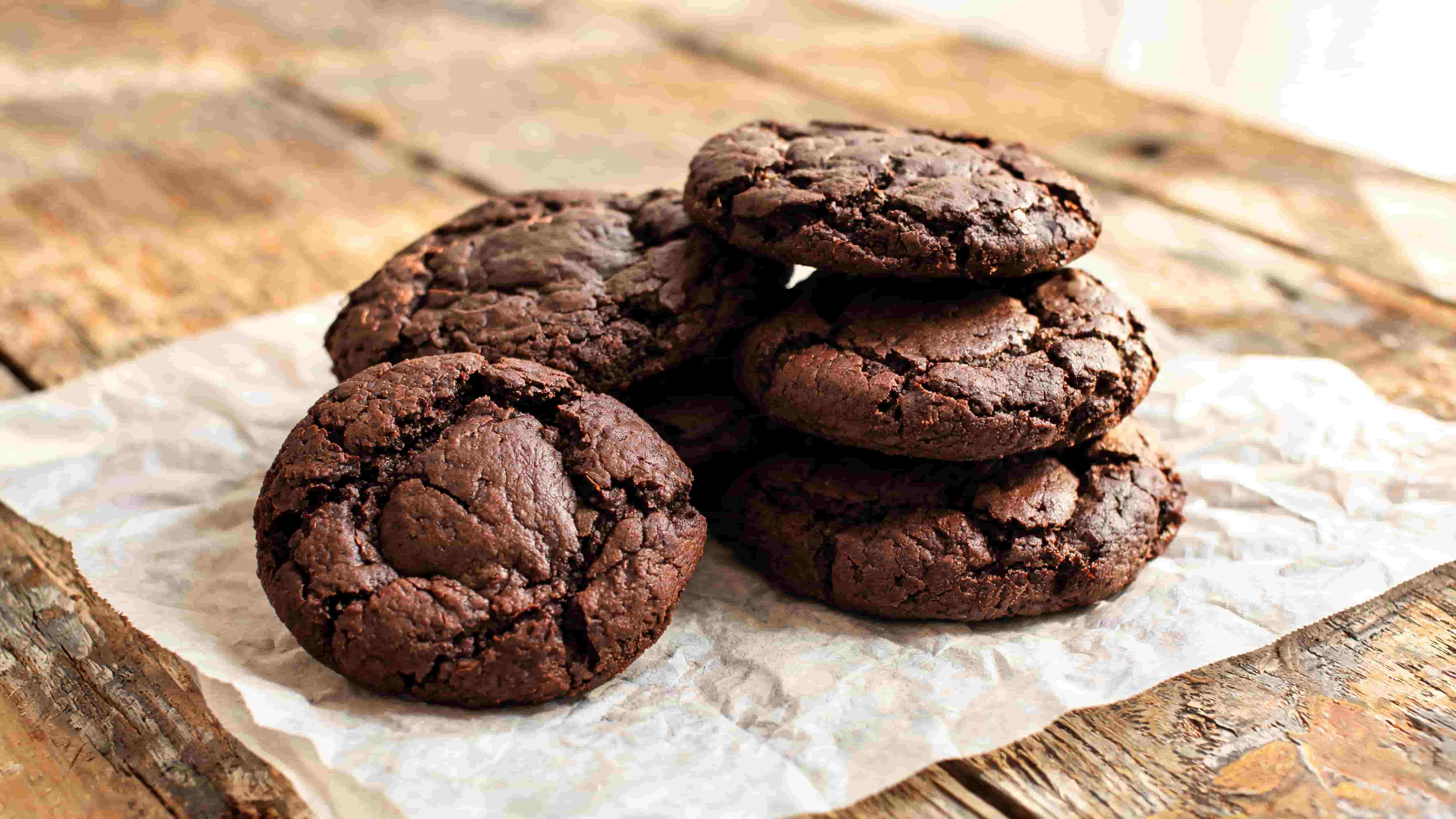 chocolate cookies stacked on parchment paper showing a rich chocolate texture with crisp edges and soft centers