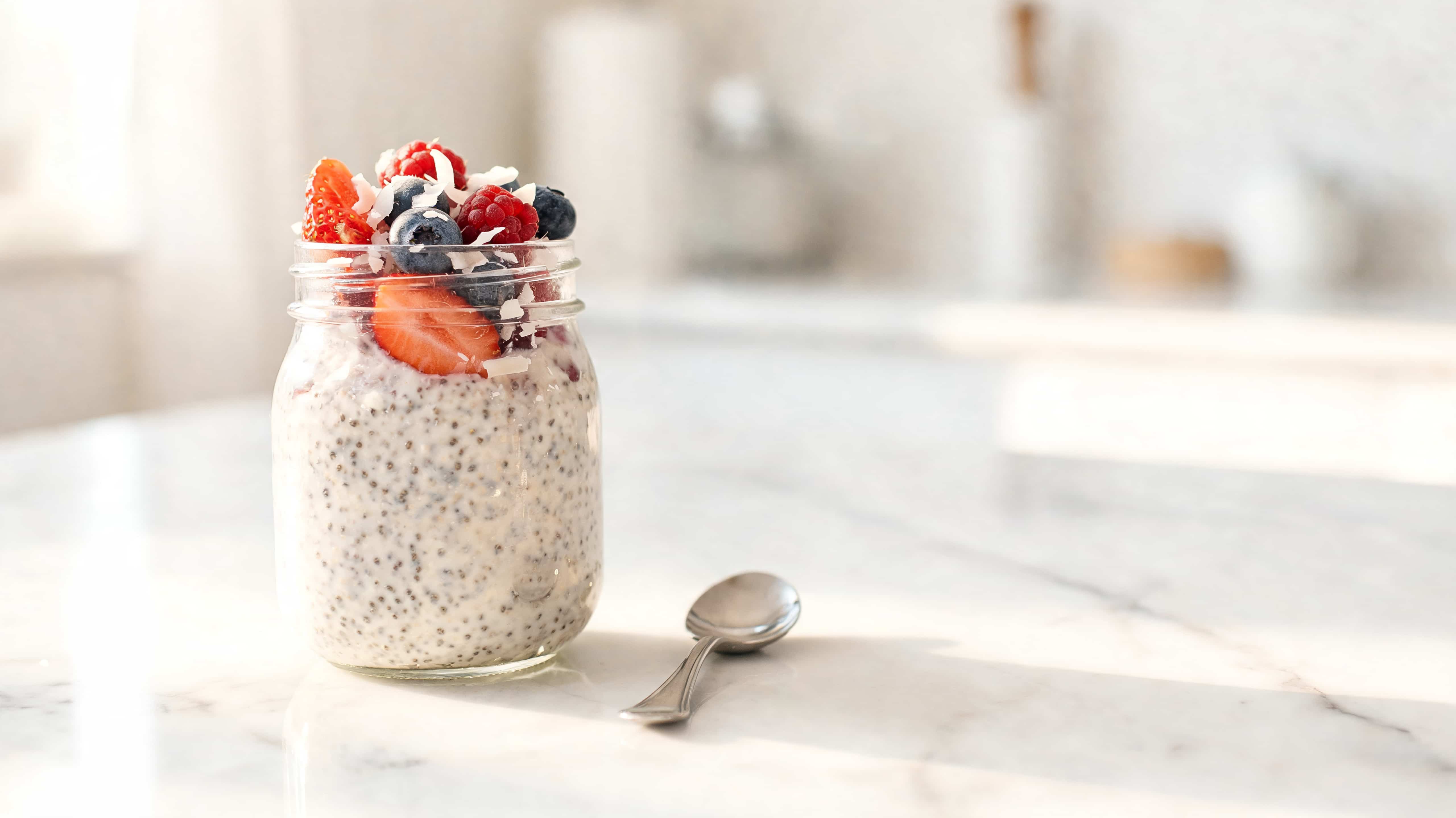 coconut chia pudding topped with fresh strawberries blueberries raspberries and shredded coconut