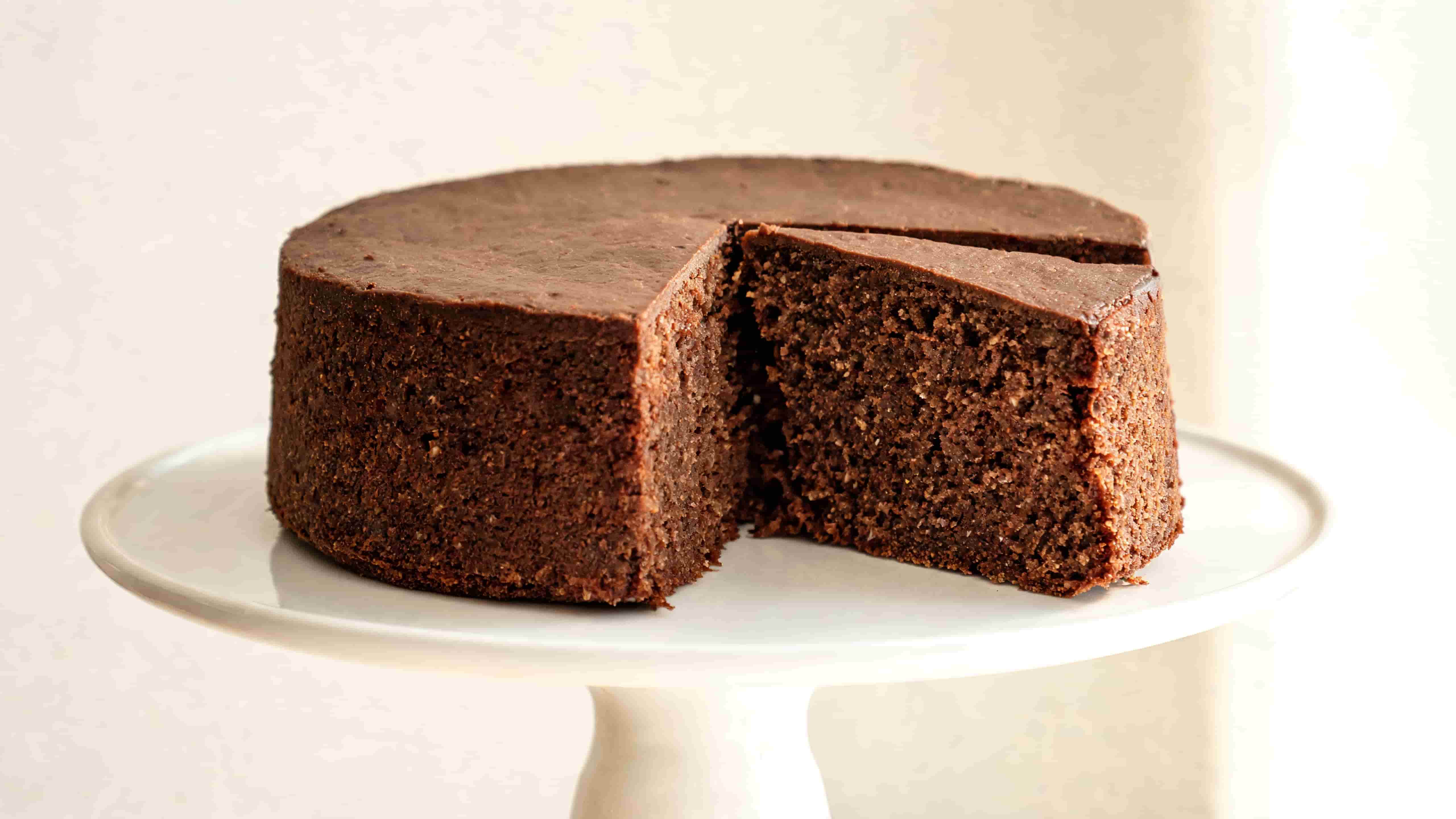 homemade chocolate cake with a smooth top and a slice removed to reveal its moist chocolate crumb