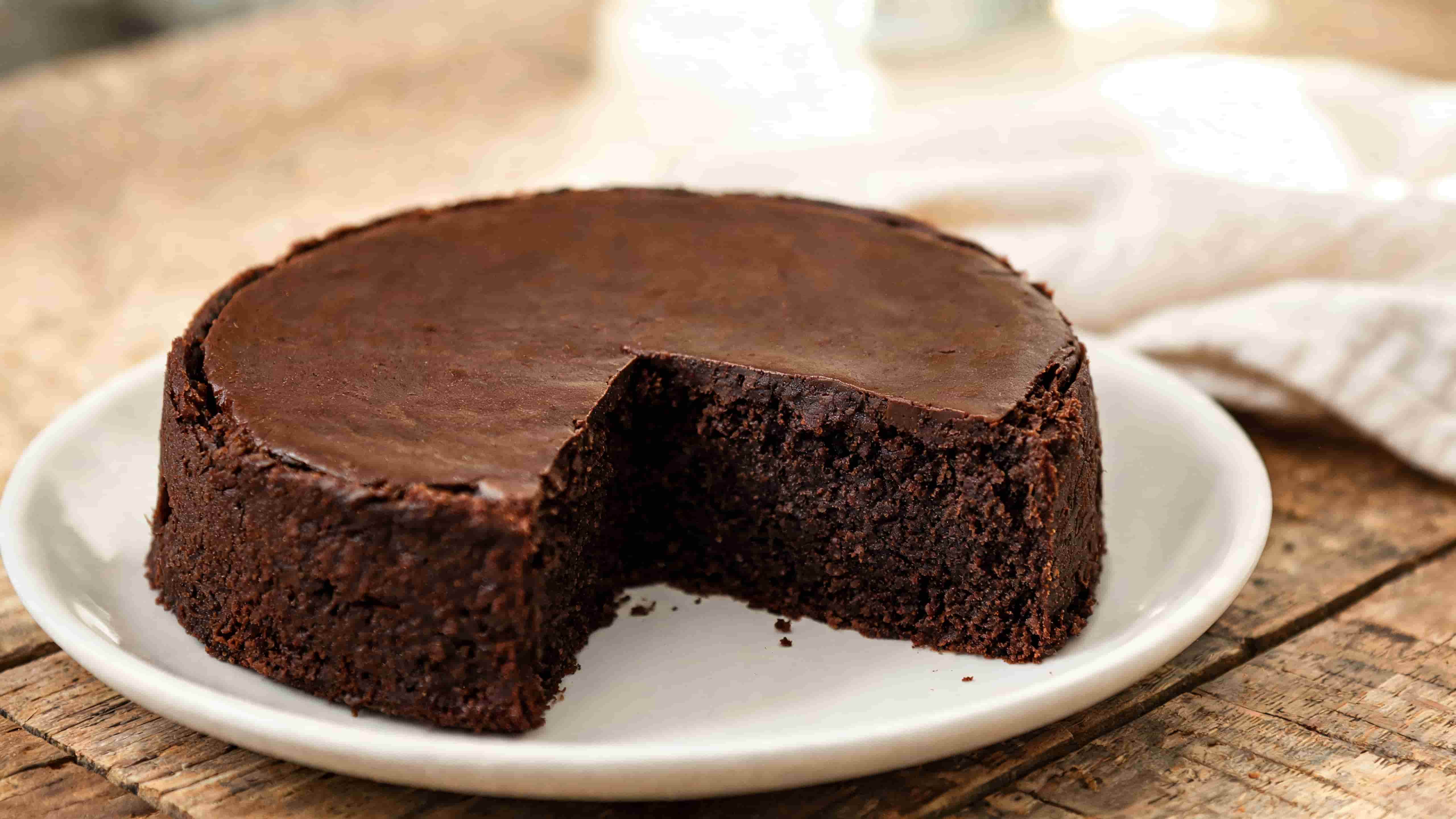 moist chocolate cake with a slice removed showing a rich fudgy center and smooth chocolate top