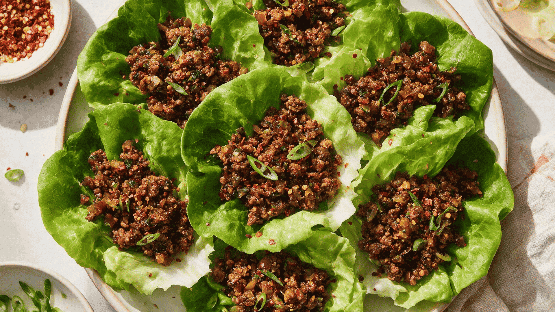 ground chicken lettuce wraps served in crisp lettuce leaves with green onions and red pepper flakes