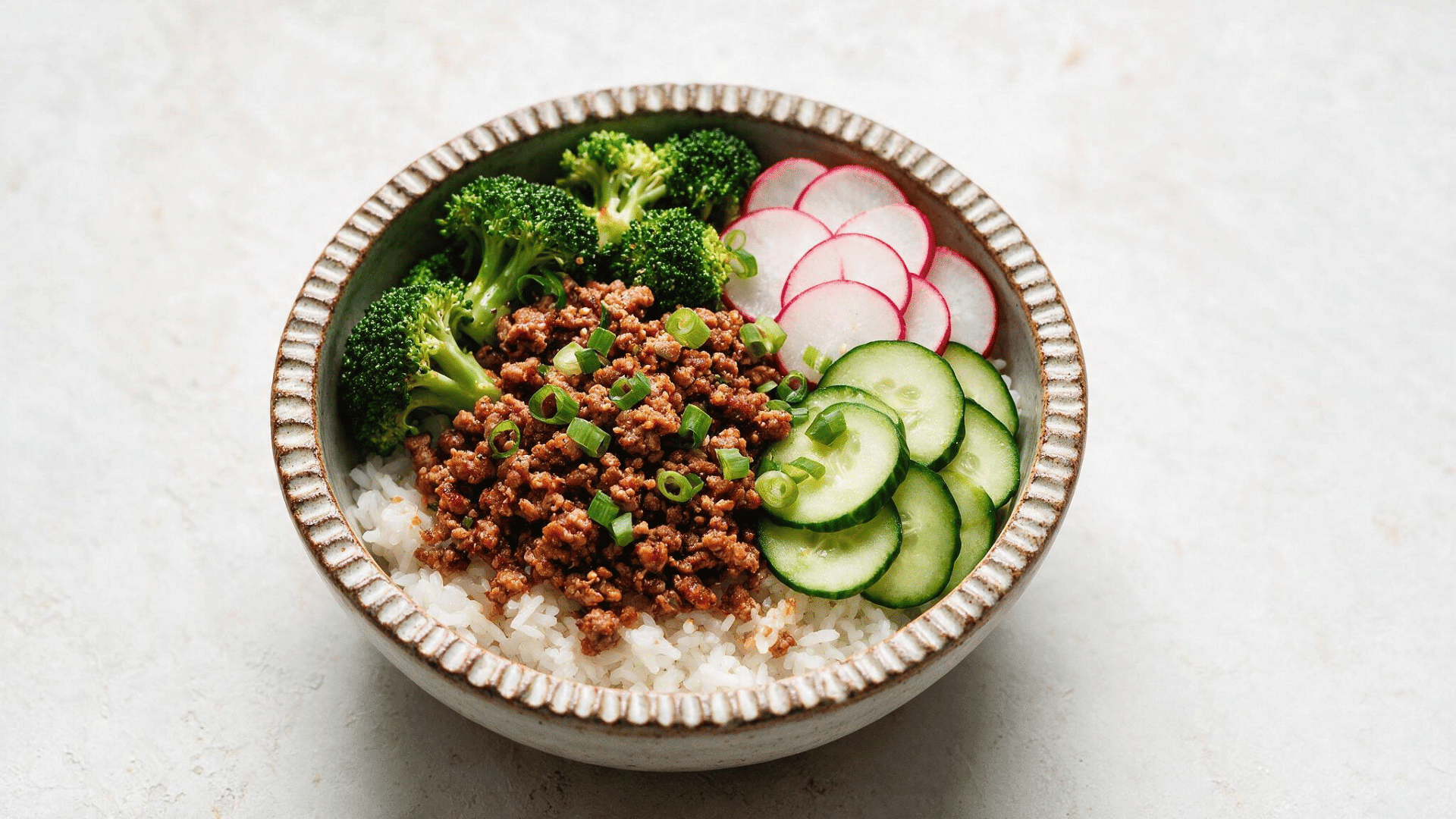 ground chicken rice bowl with white rice broccoli cucumber radishes and sliced green onions