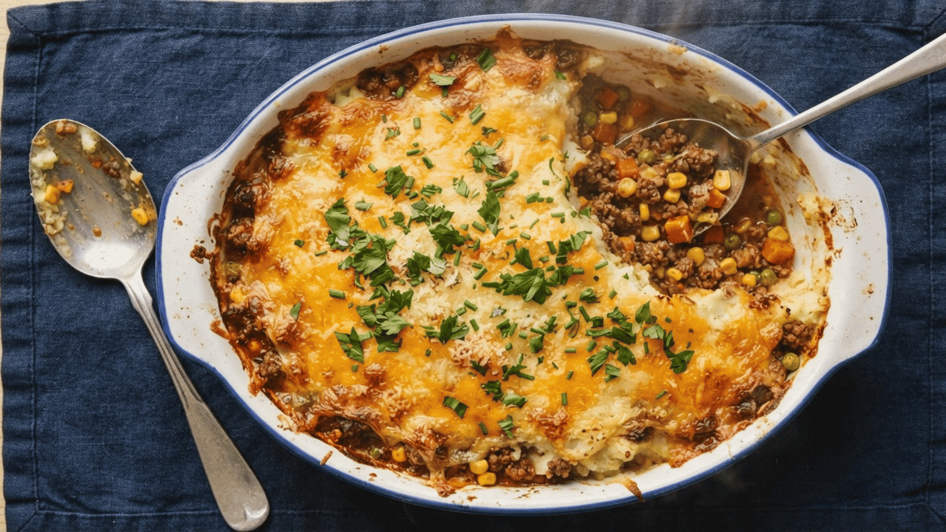 ground chicken shepherd’s pie with seasoned chicken vegetables melted cheese and fresh herbs in a baking dish