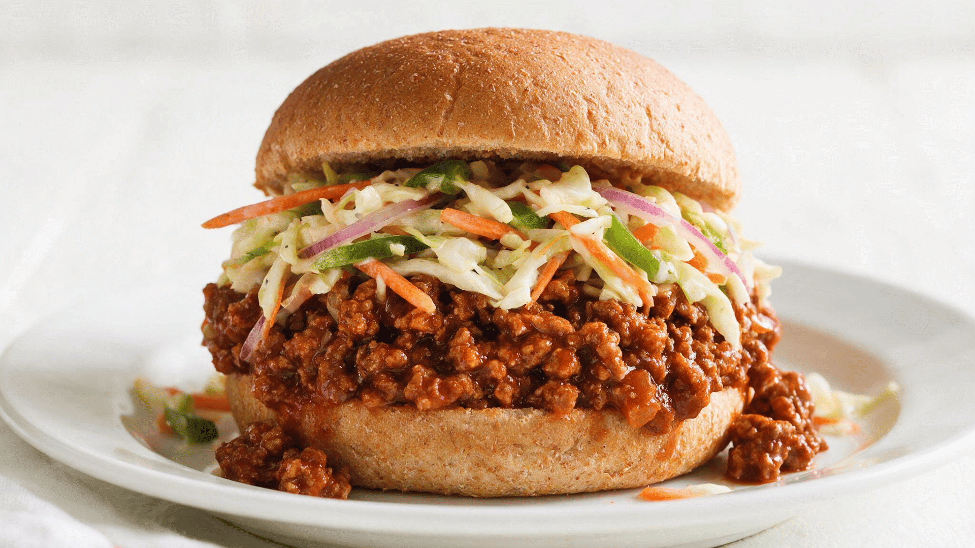 ground chicken sloppy joe on a whole wheat bun topped with fresh crunchy coleslaw