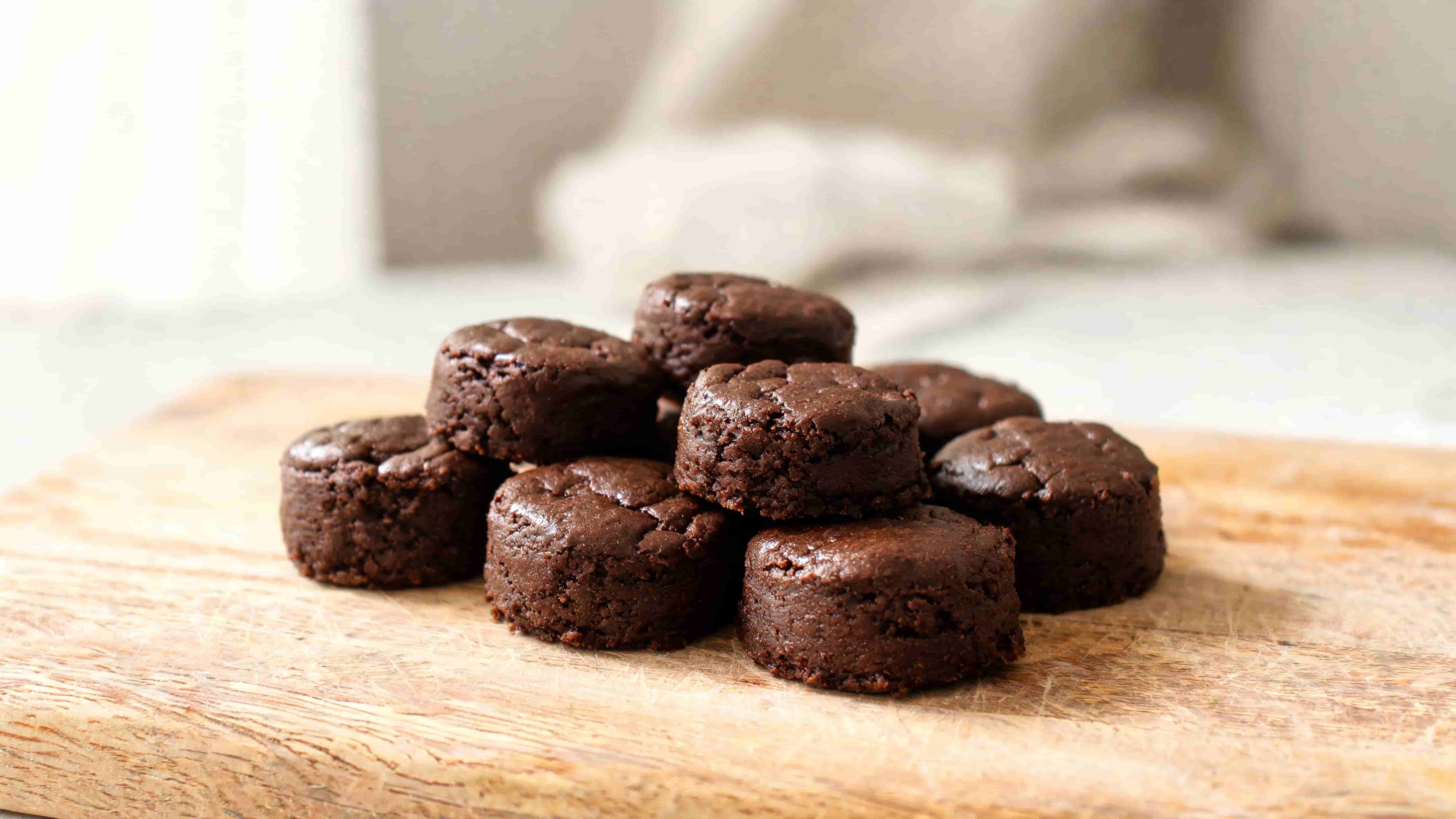 homemade chocolate brownie bites arranged on a wooden board with a dense fudgy texture and glossy tops