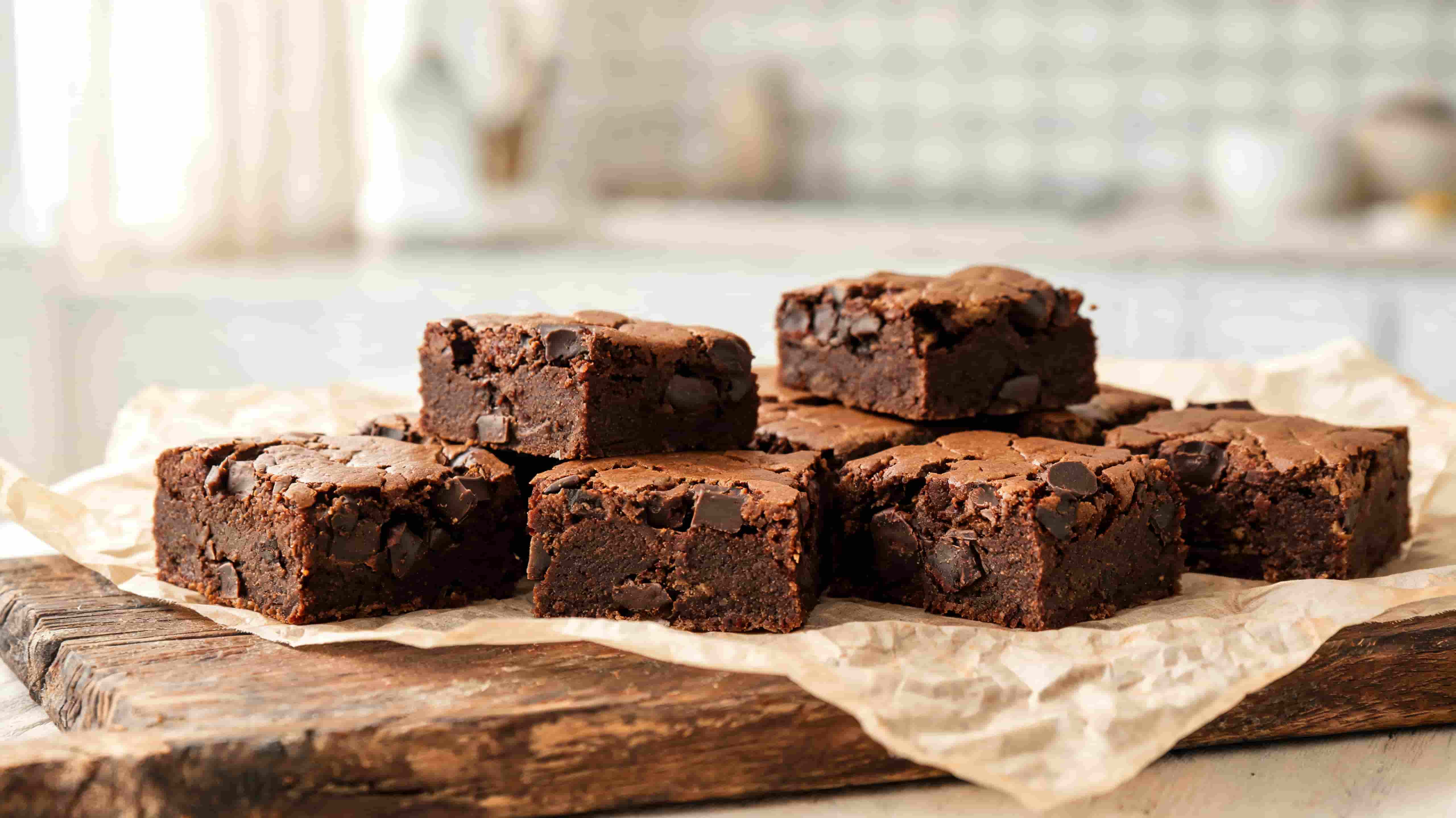 paleo brownies with a rich fudgy center and cracked chocolate top served on a wooden board for a simple dessert