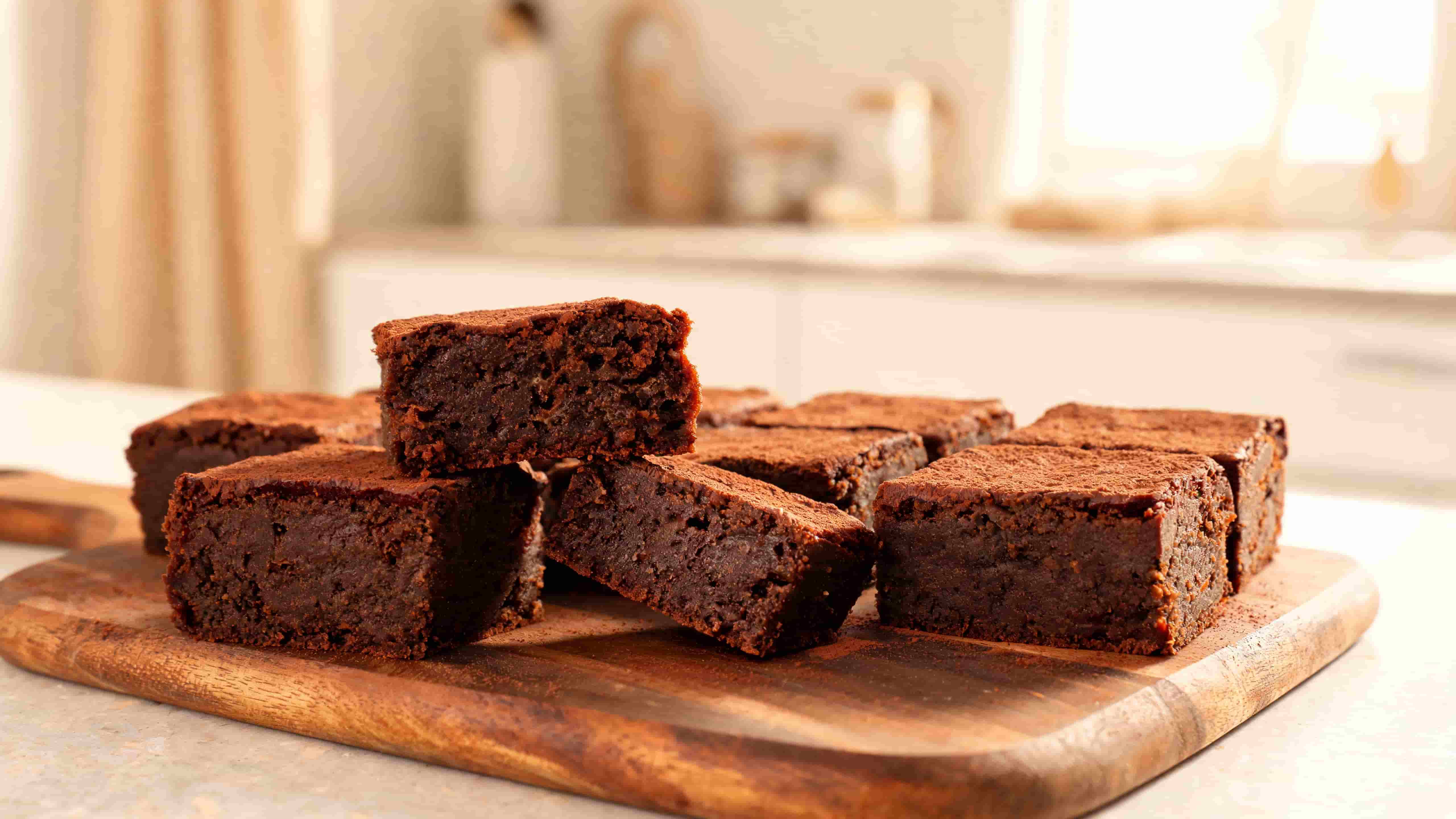 fudgy chocolate brownies cut into squares and stacked on a wooden board showing their rich moist texture