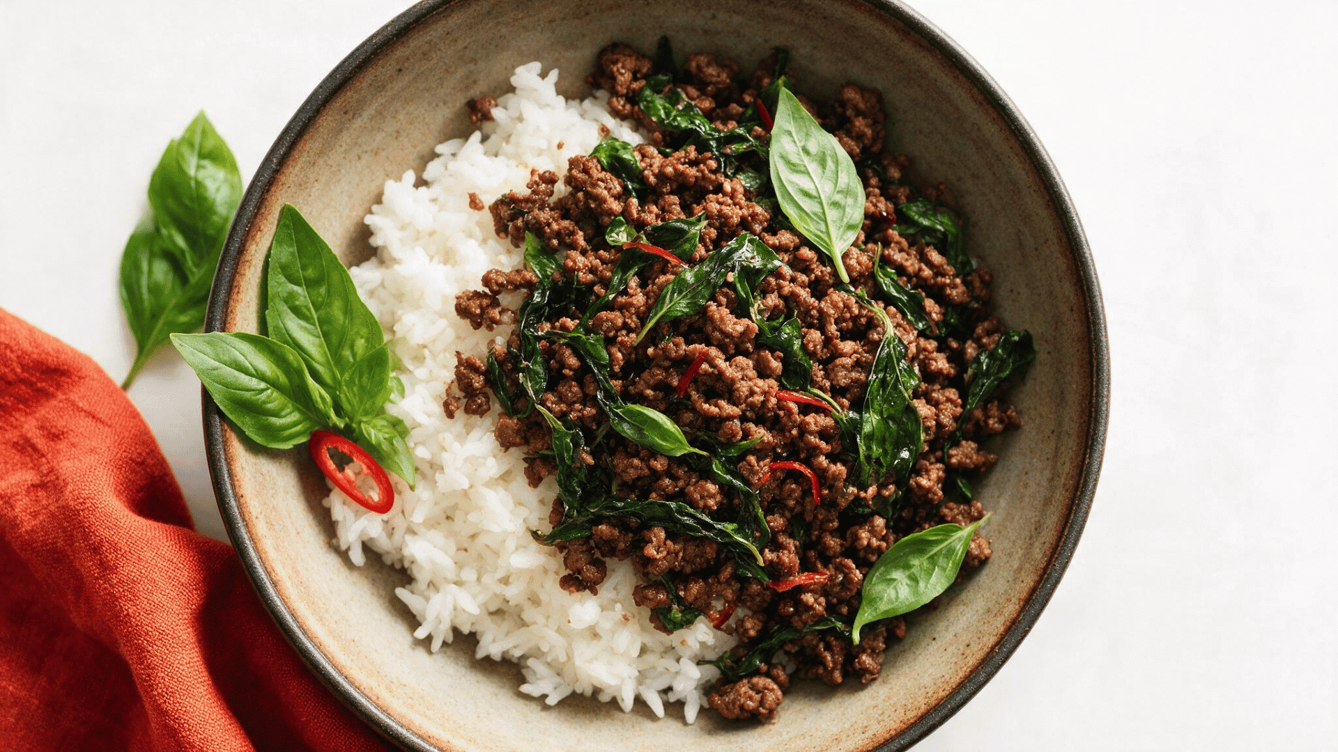 thai basil ground chicken served with white rice fresh basil leaves and sliced red chilies