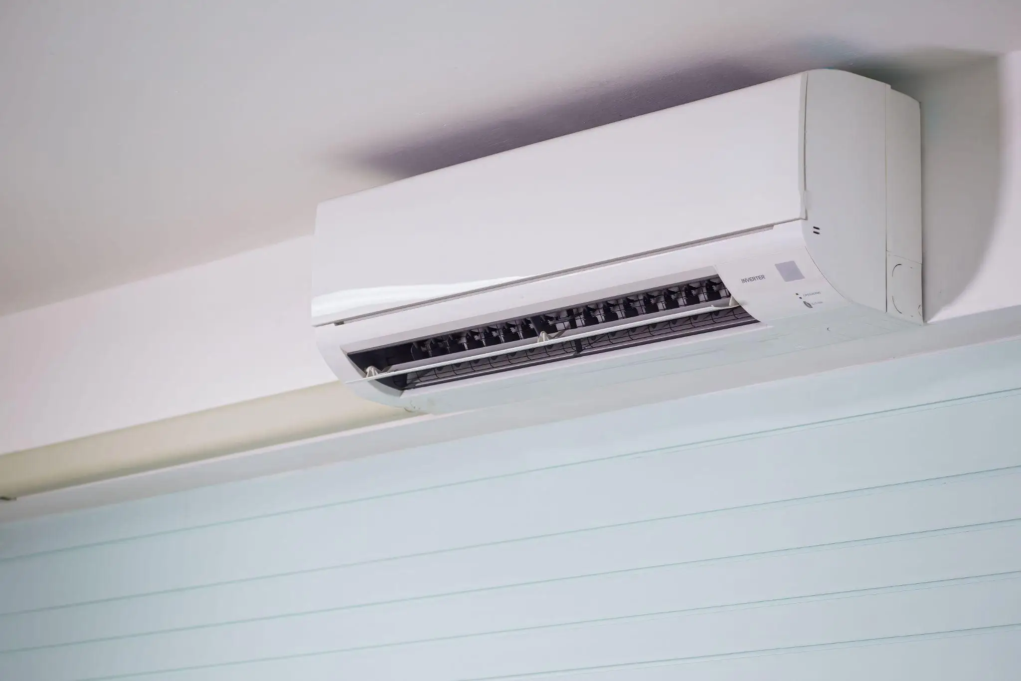 Wall-mounted inverter air conditioner in a modern interior with light blue accent wall